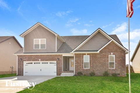 a brick house with a white garage door and a flag on a lawn