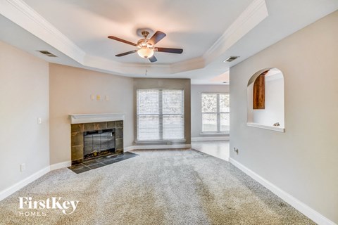 A spacious living room with a fireplace and a ceiling fan.