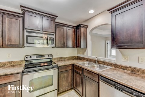 A kitchen with dark wood cabinets and a stove top oven.