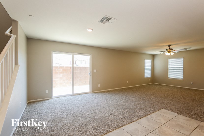 a empty living room with a ceiling fan and a sliding glass door