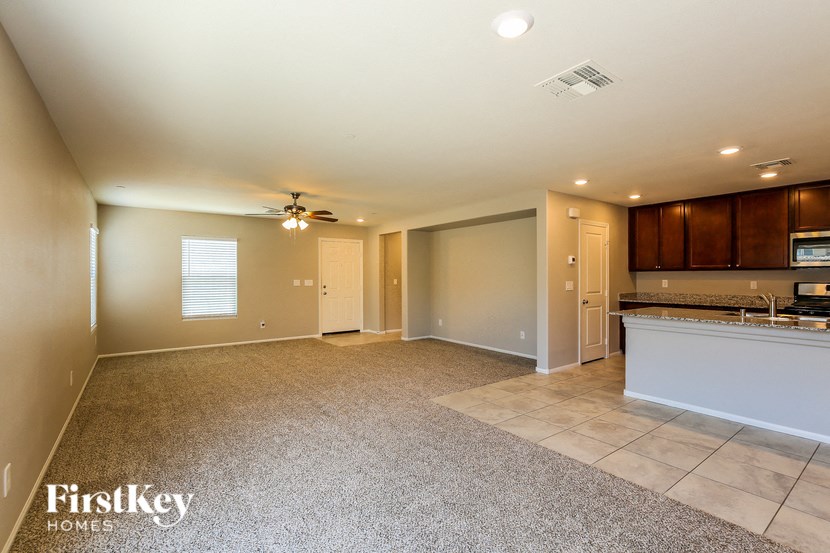 an empty living room and kitchen with a ceiling fan