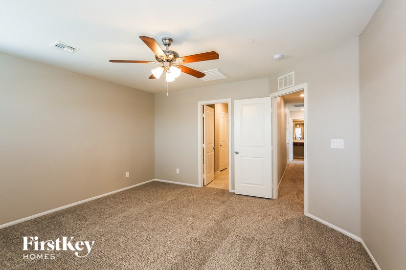 a bedroom with a ceiling fan and a door to a hallway
