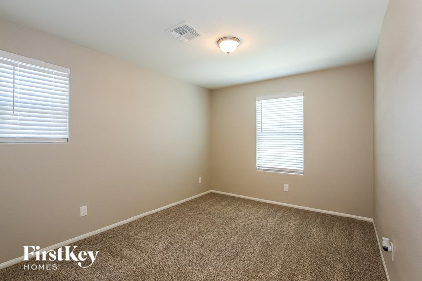 a empty room with a carpet and two windows