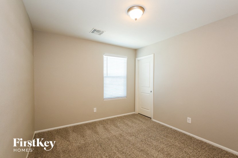 a bedroom with a door and a window and a carpeted floor