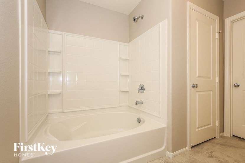 a white bathroom with a tub and a door