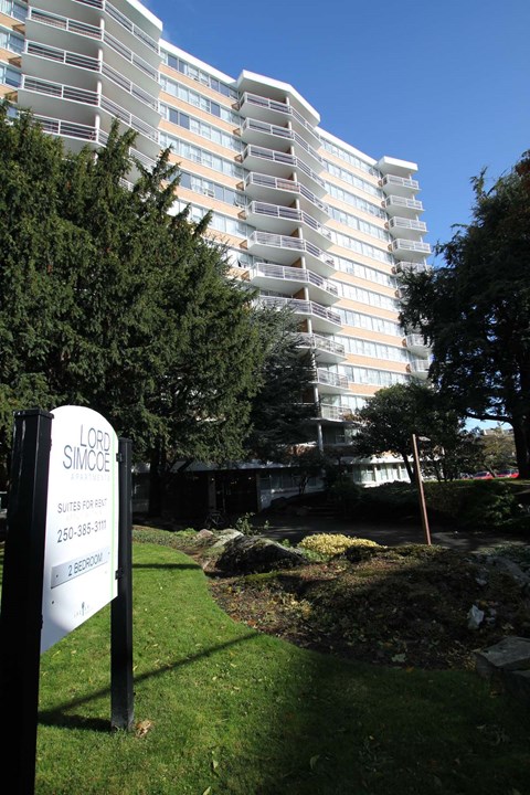a tall building in the background with a sign in the grass