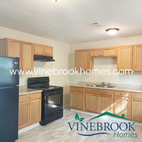 a kitchen with wooden cabinets and a black stove and refrigerator