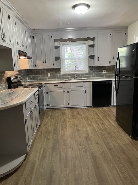 a remodeled kitchen with white cabinets and wood flooring