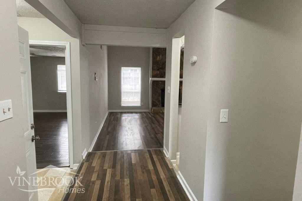 a hallway with a hard wood floor and white walls