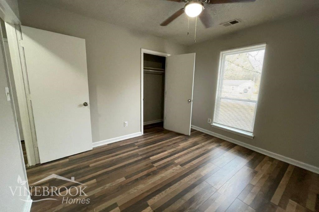 an empty living room with wood floors and a ceiling fan