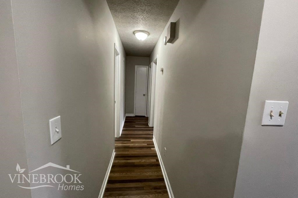 a hallway with white walls and wooden floors and a white door