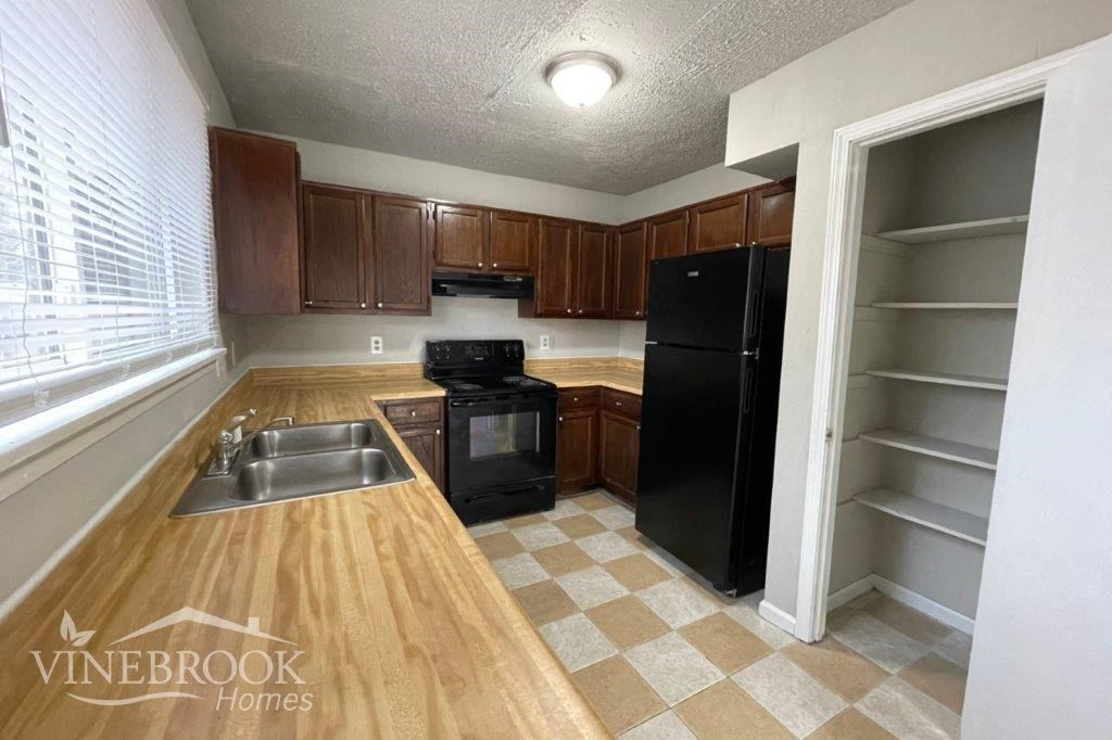 a kitchen with a sink and a black refrigerator