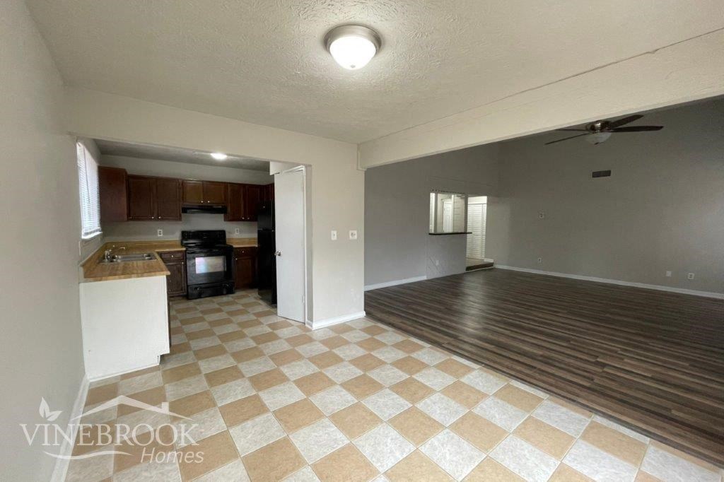 an empty living room with a checkered floor and a kitchen