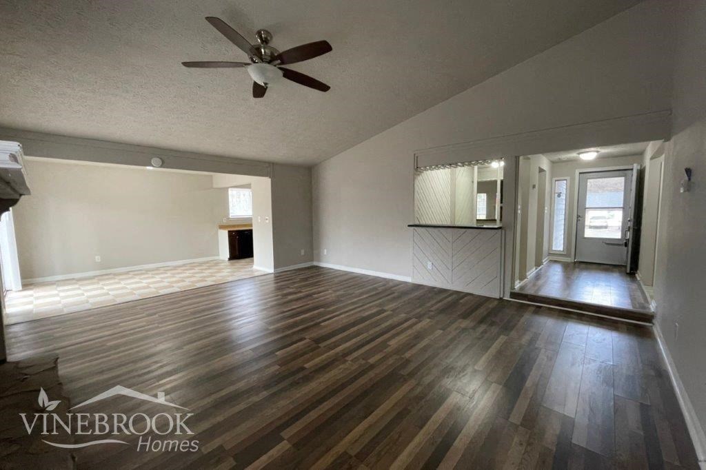 an empty living room with wood floors and a ceiling fan