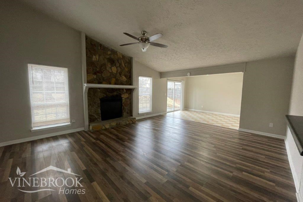 an empty living room with a fireplace and a ceiling fan
