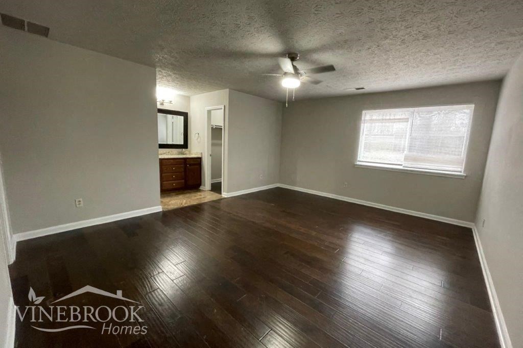 an empty living room with wood floors and a ceiling fan