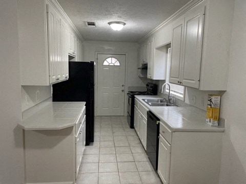 A kitchen with white cabinets and black appliances.