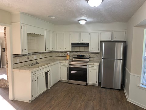 A kitchen with white cabinets and a stainless steel refrigerator.