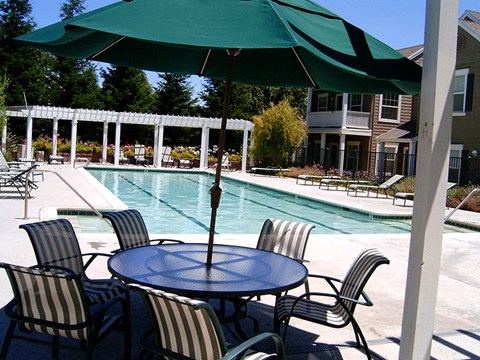 a swimming pool with a table with chairs and an umbrella