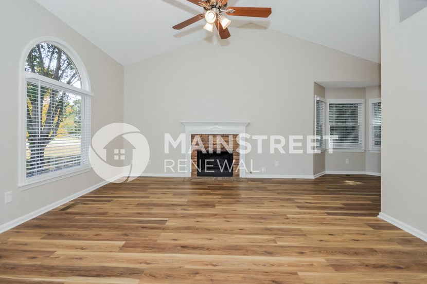 a renovated living room with hardwood floors and a ceiling fan