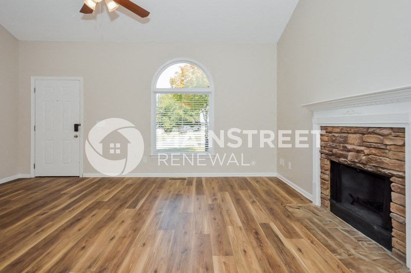 a renovated living room with a fireplace and wooden floors