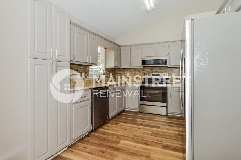 a renovated kitchen with white cabinets and stainless steel appliances