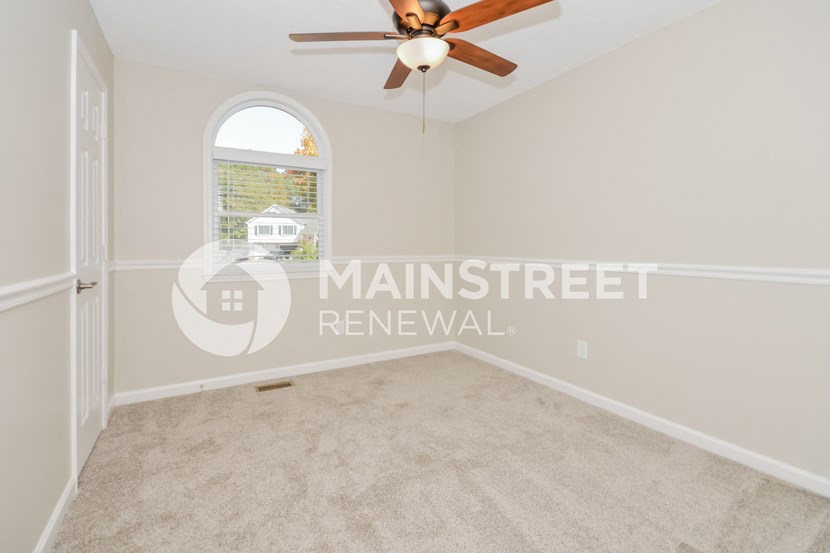 an empty living room with a ceiling fan and a window