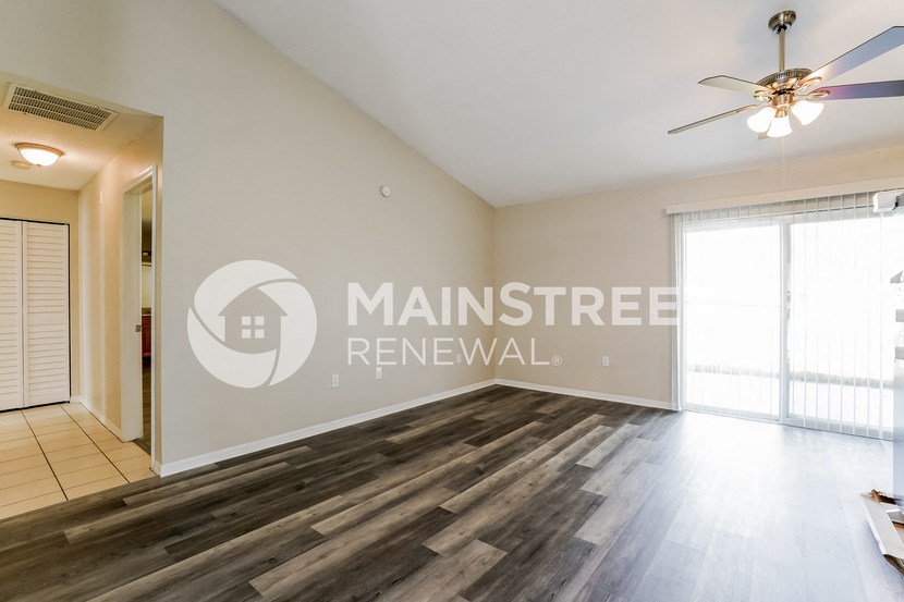 a living room with wood flooring and a door to a bedroom