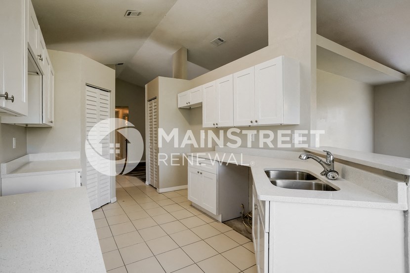 a renovated kitchen with white cabinets and a sink