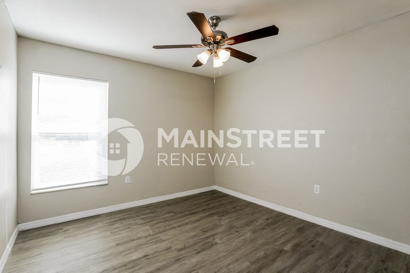 an empty living room with a ceiling fan and a window
