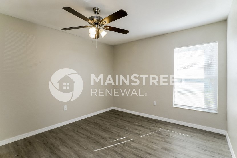 an empty living room with a ceiling fan and a window