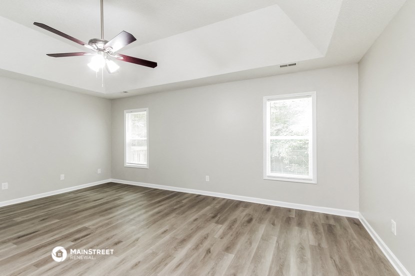 the spacious living room with hardwood floors and a ceiling fan