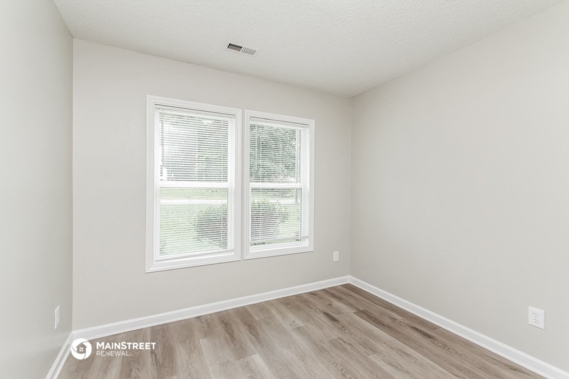 the spacious living room with two windows and wood flooring