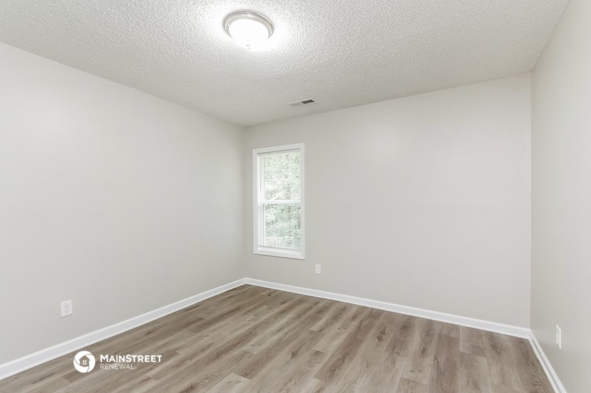the spacious living room with hardwood flooring and a window