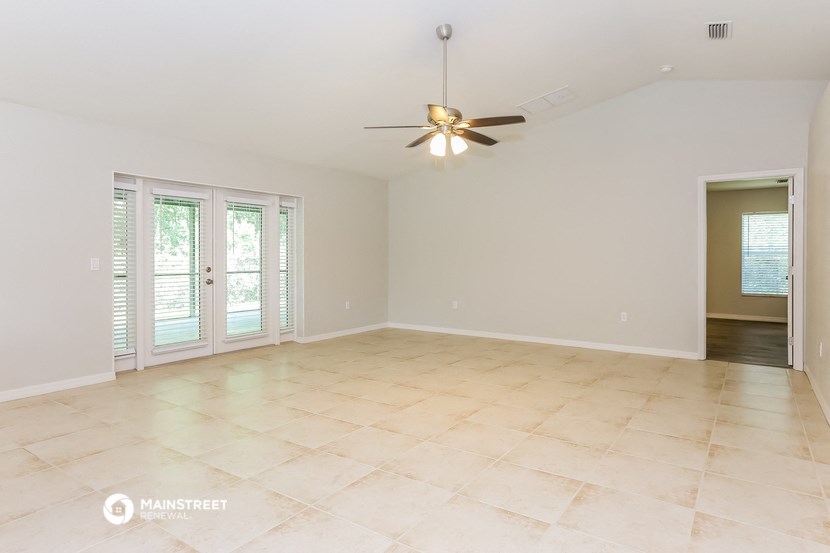 an empty living room with a ceiling fan