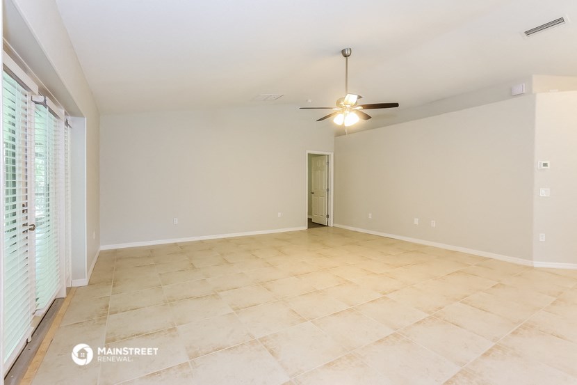 the spacious living room with tile flooring and a ceiling fan