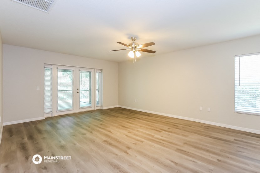 an empty living room with wood flooring and a ceiling fan