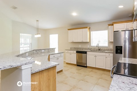 a large kitchen with marble counter tops and stainless steel appliances