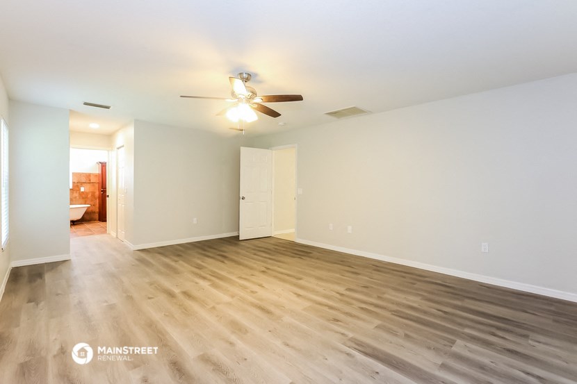 a spacious living room with wood flooring and a ceiling fan