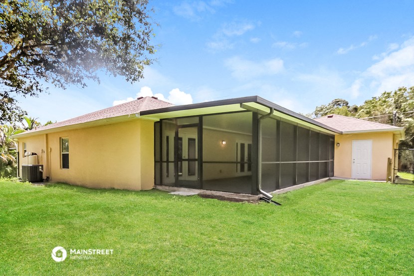 a yellow house with a lawn and a glass screened porch
