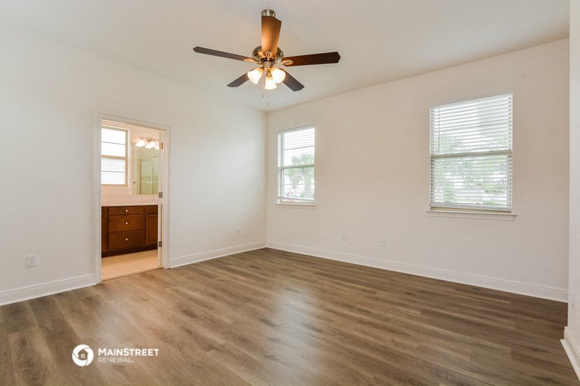 the spacious living room with wood flooring and a ceiling fan