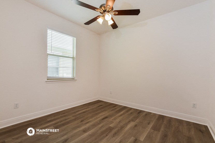the bedroom of our studio apartment atrium with wood flooring and a ceiling fan