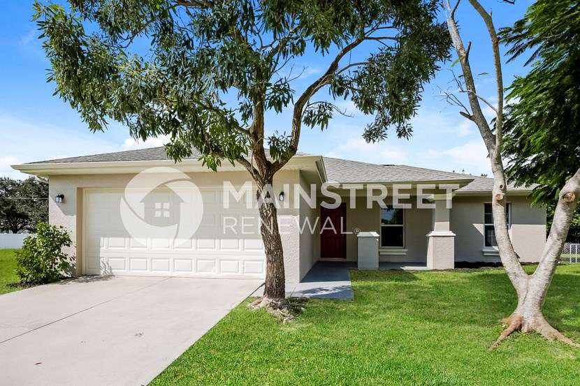 a house with a garage and a tree in front of it