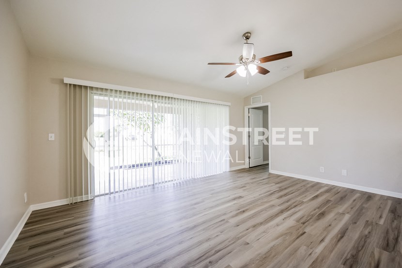 a living room with hardwood floors and a large window and a ceiling fan