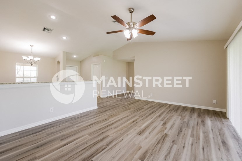 a renovated living room with hardwood floors and a ceiling fan