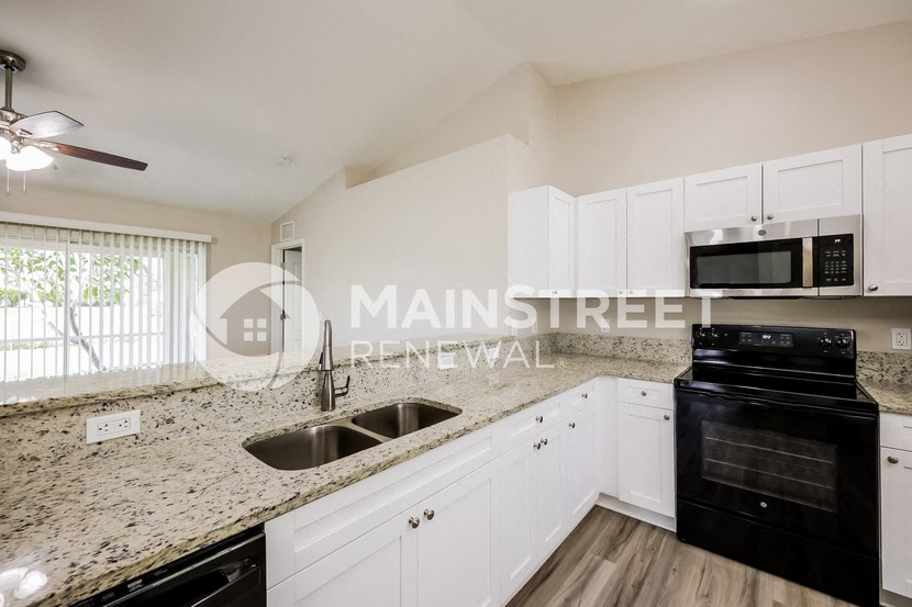 a kitchen with granite counter tops and white cabinets