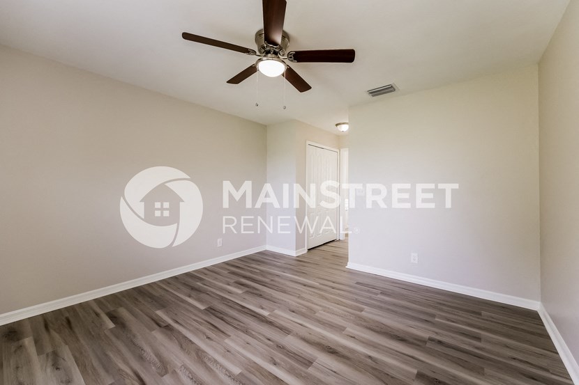 a renovated living room with hardwood floors and a ceiling fan
