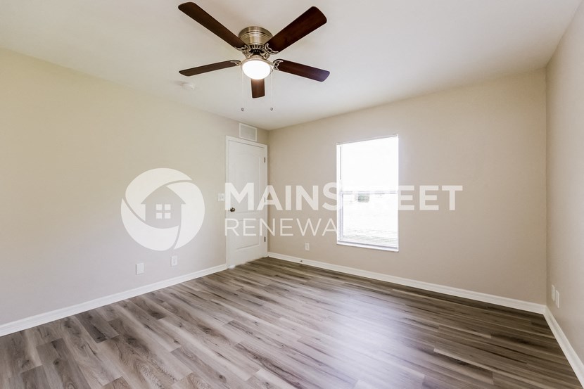 a living room with wood floors and a ceiling fan