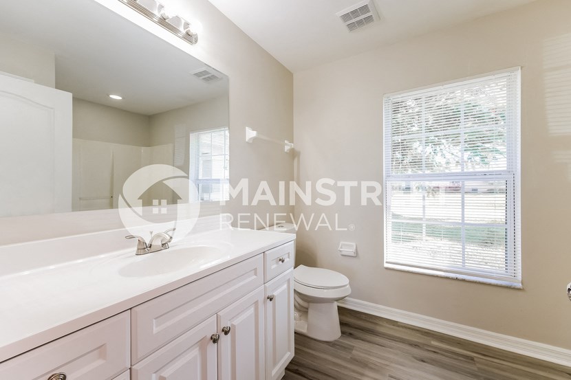 a white bathroom with a toilet and sink and a window