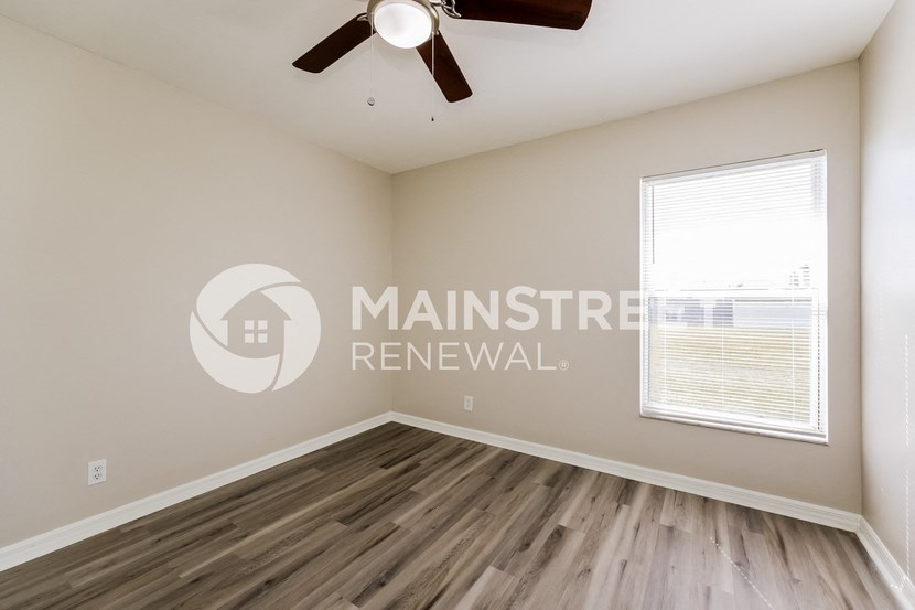 a bedroom with a large window and a ceiling fan